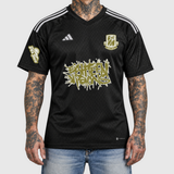 Gold Adidas football shirt model front mockup: original artwork composited onto an AI-generated tattooed model wearing blue jeans. Neutral light gray background.