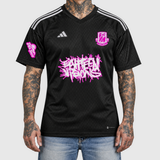 Pink Adidas football shirt model front mockup: original artwork composited onto an AI-generated tattooed model wearing blue jeans. Neutral light gray background.