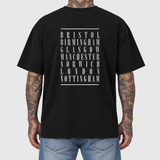 UK Tour model back mockup: original artwork composited onto a realistic black cotton shirt worn by an AI-generated tattooed model. Neutral light gray background.